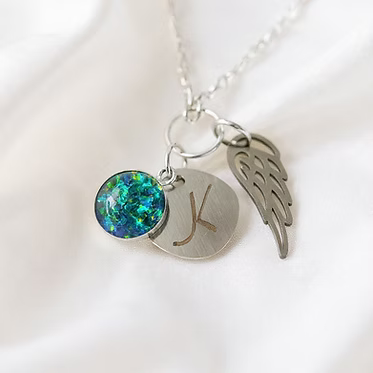  Cremation Initial Charm Angel Wing Pendant in .960 Silver.  Each piece features an opal accent and a delicate angel wing, symbolizing peace and protection. 
