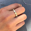A hand holding a silver Eternity ring with a white and yellowish stone inlay