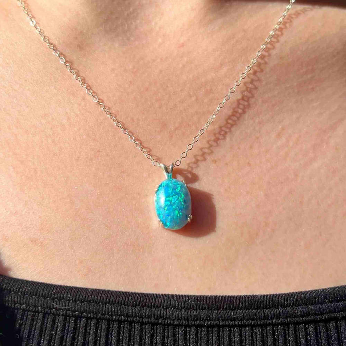A sterling silver four-prong opal pendant with a chain.