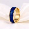 A gold band ring featuring a textured dark blue inlay, displayed on a soft white fabric background.