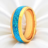 A gold-plated ring band featuring a vibrant blue glitter inlay, shown on a white satin background.