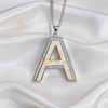 A silver letter 'A' pendant necklace with a white iridescent inlay and clear rhinestone accents, displayed on a draped white satin fabric background.