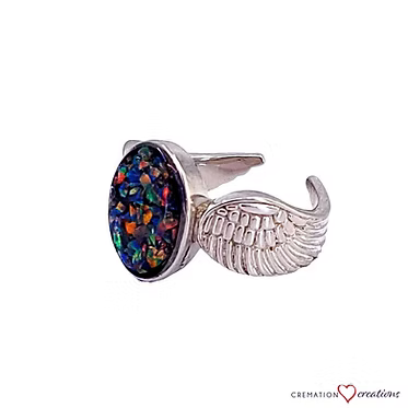 A silver ring featuring a textured wing design on one side and an oval black opal stone with multicolored iridescent flecks on the other, shown against a plain white background.
