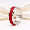 A polished silver band ring featuring a vibrant red textured inlay, displayed on a soft white satin ribbon.
