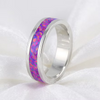 A polished silver band ring featuring a vibrant purple and pink iridescent inlay, resting on a soft white fabric background.