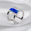 A polished silver-tone open cuff ring featuring a rectangular blue opal inlay, displayed on a soft white fabric background.