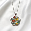 A silver-tone flower-shaped pendant necklace with colorful enamel floral details, displayed on a white satin fabric background.