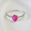 A silver ring with a textured twisted band and a central teardrop-shaped pink gemstone, shown on a clean white background.