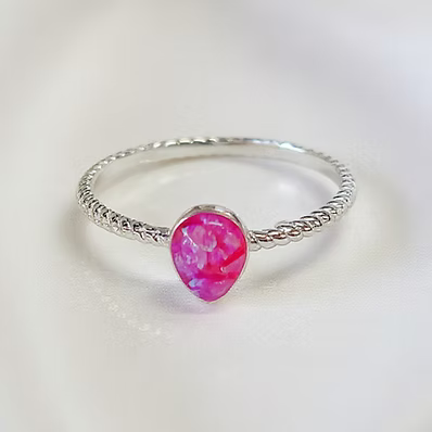 A silver ring with a textured twisted band and a central teardrop-shaped pink gemstone, shown on a clean white background.