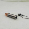 A bullet-shaped pendant necklace made of silver-colored metal, shown disassembled with a copper-colored bullet tip and a silver chain attached, resting on a white textured surface.