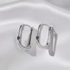 A pair of silver-toned hoop earrings with small purple gemstone accents, displayed on a white satin fabric background.
