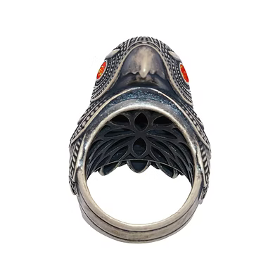 A gothic-style silver ring shaped like a bird's head with textured detailing and small red gemstone eyes, shown against a plain white background.