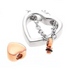 A silver heart-shaped ring with a chain and a dangling rose gold heart charm, shown alongside a separate rose gold heart-shaped bead on a white background.