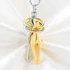 A two-tone gold and silver pendant necklace featuring a stylized figure design, displayed on a white satin fabric background.