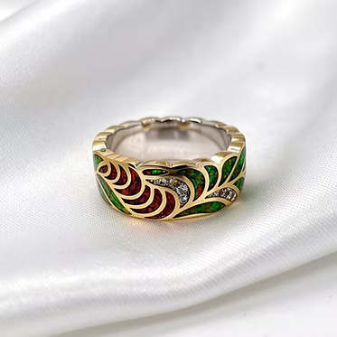 Silver played brass alloy with a leaf-like pattern inlaid with green, red, and clear stones, resting on a white satin fabric background
