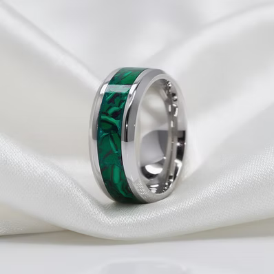 A silver-toned ring with a polished green inlay, displayed on draped white satin fabric.