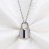 A silver padlock pendant necklace resting on a white textured fabric background.