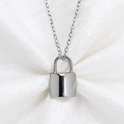 A silver padlock pendant necklace resting on a white textured fabric background.