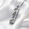 A silver rectangular pendant necklace with a wing design and iridescent inlay, resting on white satin fabric.