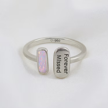 A silver open ring with two rectangular ends, one featuring a small iridescent opal-like inlay and the other engraved with 'Forever Missed' and a small '925' mark inside, shown on a white background.