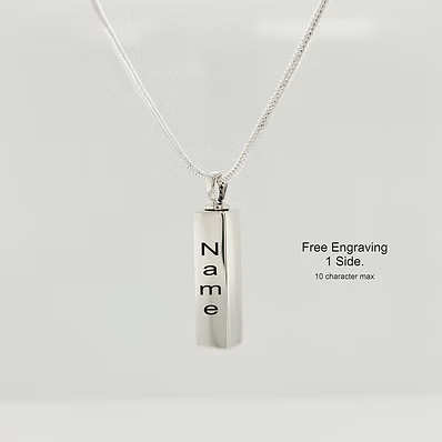 A silver vertical rectangular pendant necklace engraved with the name 'Name' in black lettering, suspended from a delicate silver chain against a light gray background. To the right, black text reads 'Free Engraving 1 Side.