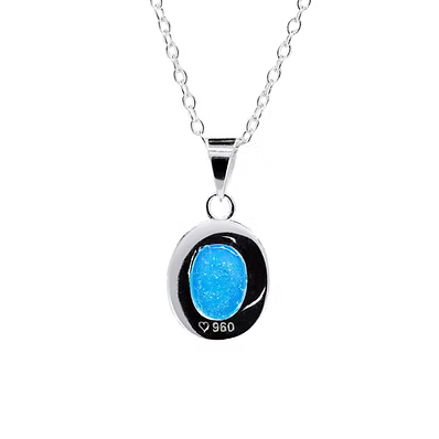 A silver oval pendant necklace featuring a vibrant blue glittery center stone, with '925' sterling silver stamped on the side, shown against a plain white background.