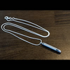 A silver-toned metal pendant necklace with a cylindrical bullet-shaped charm on a dark brown wooden surface.