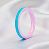 A pink resin ring with a textured turquoise blue inlay, standing upright on a draped white satin fabric background.