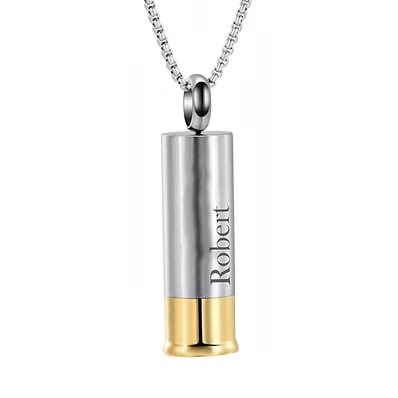 A silver cylindrical urn pendant necklace designed like a shotgun shell, with a gold base and the name 'Robert' engraved on the side, shown on a white background.