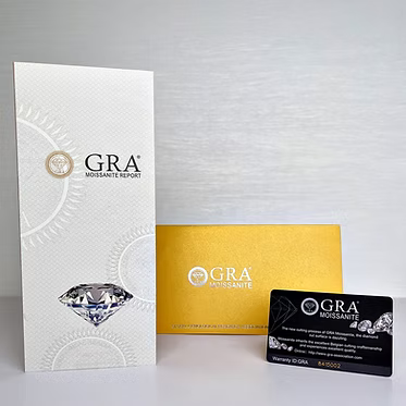 GRA Moissanite Report card, a gold Moissanite Report envelope, and a black Moissanite Certificate card arranged on a light gray background.