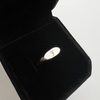 A silver oval pendant with engraved lettering, displayed inside an open black velvet jewelry box on a light gray background.