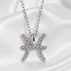 A silver-toned Pisces zodiac sign pendant necklace adorned with small clear crystals, displayed on a white satin fabric background.