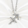 A silver-toned Sagittarius zodiac sign pendant necklace paved with small clear stones, displayed on a white satin fabric background.