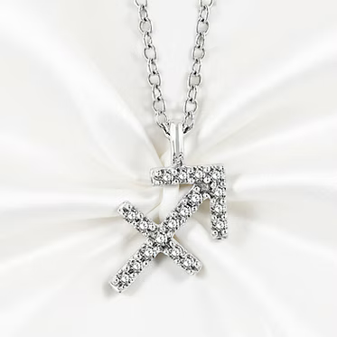 A silver-toned Sagittarius zodiac sign pendant necklace paved with small clear stones, displayed on a white satin fabric background.