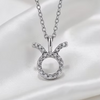 A silver-toned necklace with a Zodiac Aries pendant, featuring a halo of small clear stones around an open circle with curved horns, displayed on a white satin fabric background.